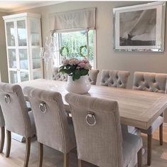 a dining room table and chairs in front of a large window with flowers on it