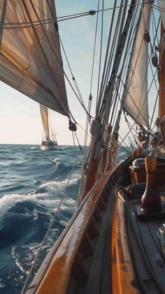 two sailboats sailing in the ocean on a sunny day