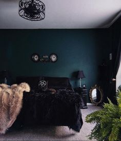 a bedroom with dark green walls and black fur on the bed, along with plants