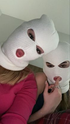 two women with white masks on their faces and one has her finger in the other's mouth