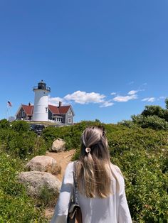 a woman walking down a path towards a lighthouse