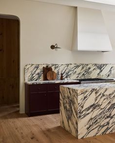 a kitchen with marble counter tops and wooden flooring in front of an oven hood