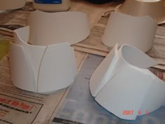 two white vases sitting on top of a table next to paper and glue bottles