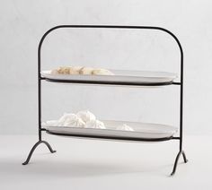 two tiered trays with white plates on each one and black metal stand holding food