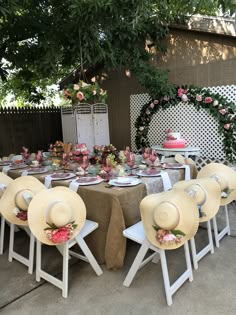 a table set up with hats on it and flowers around the tables for an outdoor party