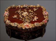 an elaborately decorated wooden box with gold trimmings and jewels on the lid