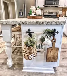 a kitchen island with potted plants on it and cutting boards hanging from the top