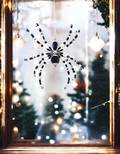 a spider is hanging from the side of a window in front of a christmas tree