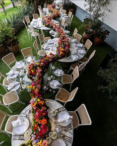 a long table is set up with flowers and place settings for an outdoor dinner party