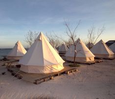 a group of white tents sitting on top of a sandy beach