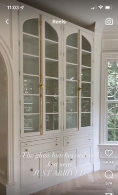 a white china cabinet with gold trim and glass doors