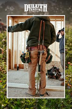 a man standing in front of a building with tools on his back and an image of him