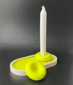 a white candle sitting on top of a yellow plate next to a green donut