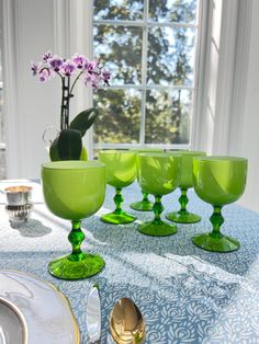 a table topped with green glasses and plates