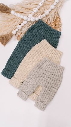 three pairs of knitted leggings with tassels and beads on them