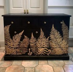 a black dresser with gold leaf designs on it