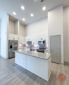 an empty kitchen with white cabinets and stainless steel appliances in the middle of the room