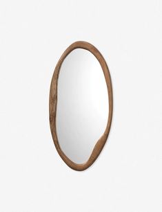 an oval wooden mirror hanging on the wall