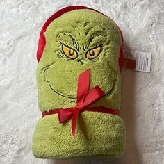 a green grin face stuffed animal with a red ribbon around it's neck and eyes