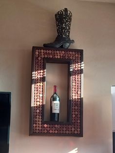 a bottle of wine sitting on top of a wooden frame in front of a mirror