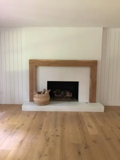 an empty living room with wood flooring and a fire place in the middle of the room