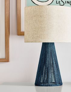 a blue table lamp sitting on top of a white table next to a framed photo