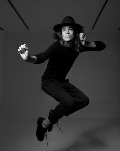 a woman jumping in the air while wearing a hat and black shirt with long sleeves