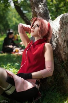 a woman sitting on the ground next to a tree with headphones in her ears