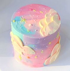 a pink and blue cake with white frosting on it's sides, decorated with stars