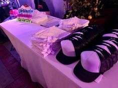 there are many hats and shoes on display at the table with purple lighting behind them