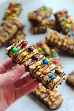 a hand holding up a cookie bar with m & m candy bars on the top