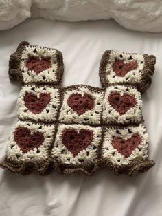 there is a crocheted square with hearts in it on top of a bed