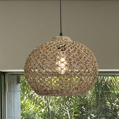 a light fixture hanging from a ceiling in a room with trees and plants behind it