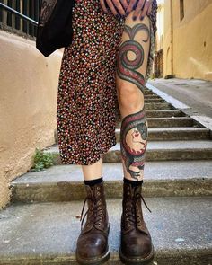 a woman with tattoos on her legs and leggings standing in front of some steps