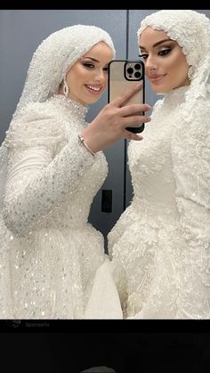 two women dressed in white are taking a selfie