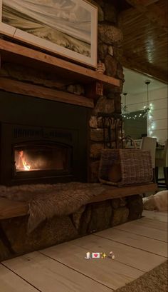 a fire place in a living room with logs on the mantle and wood flooring