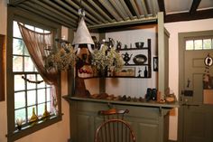 an old fashioned kitchen with green cabinets and wooden chairs in front of the counter top