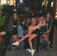 a group of young women sitting around each other in front of a bar at night