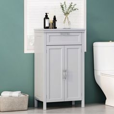 a white toilet sitting next to a wooden cabinet in a green room with blue walls