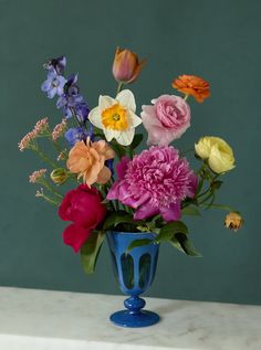 a blue vase filled with lots of colorful flowers