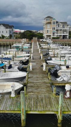 several boats are docked at a pier in front of some houses on the other side