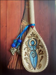 a wooden spoon with an ornate design on it and a blue ribbon hanging from the handle