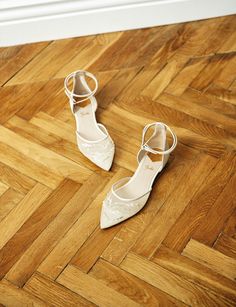 two pairs of white shoes sitting on top of a wooden floor