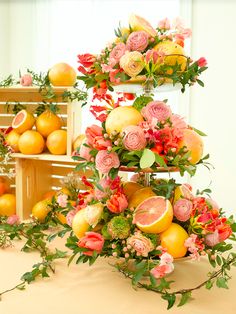 an arrangement of flowers and fruit on display