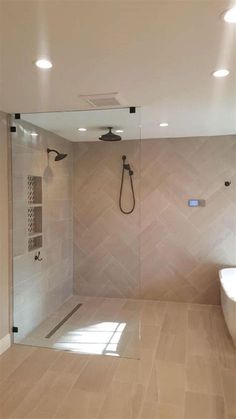 a bathroom with a walk in shower next to a white bathtub and wooden floors