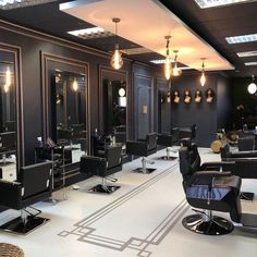 a hair salon with black chairs and chandeliers