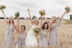 a group of women standing next to each other in a field holding flowers and bouquets