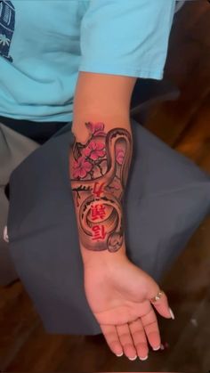 a woman's arm with a tattoo on it that has a snake and flowers on it