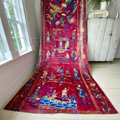 a red cloth covered in an elaborately designed design is sitting on the floor next to a window