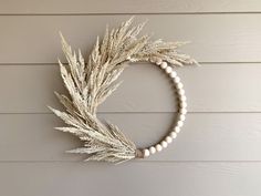 a wreath with white beads hanging on the side of a house